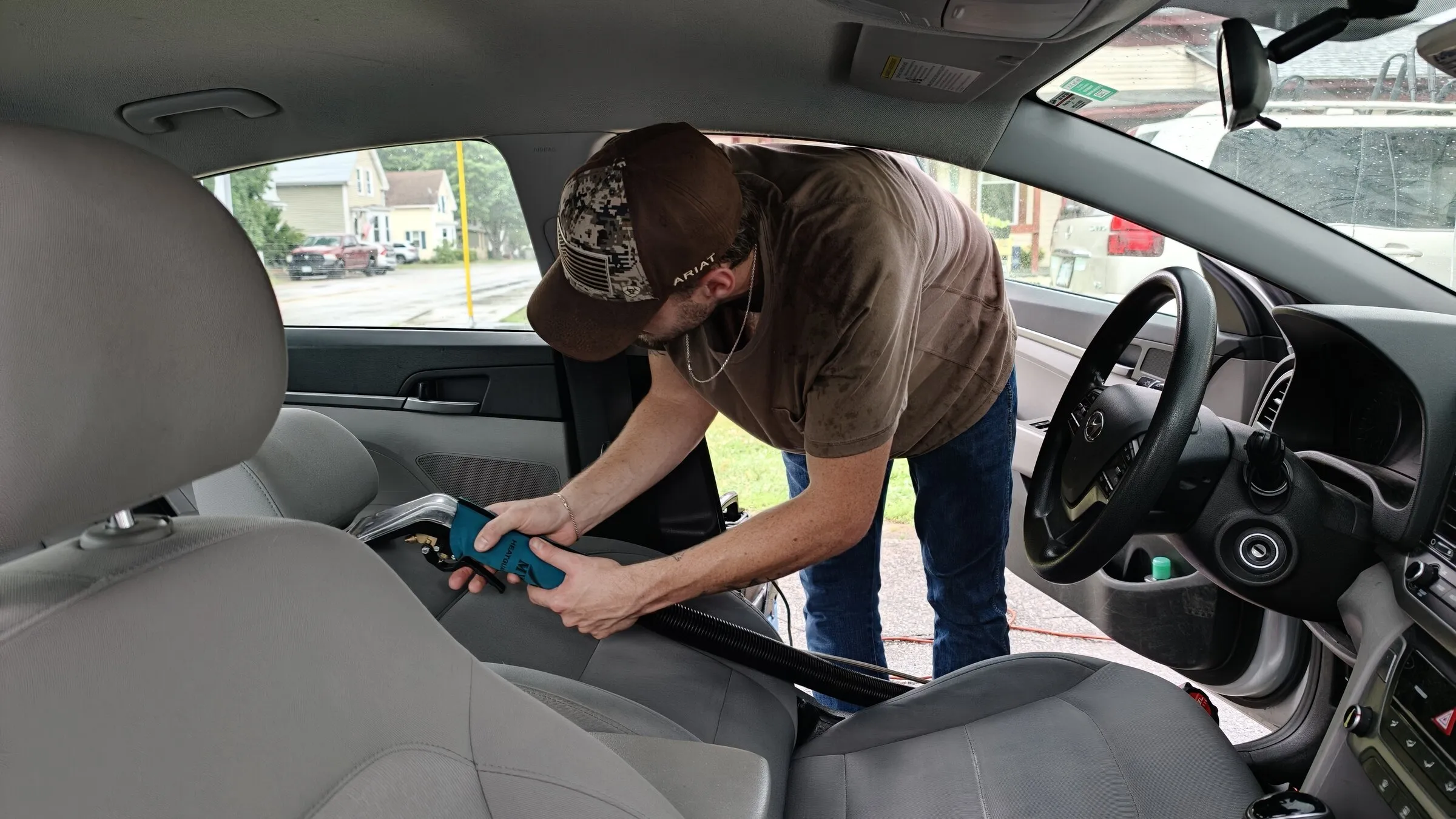 Detailer cleaning a car interior while being filmed